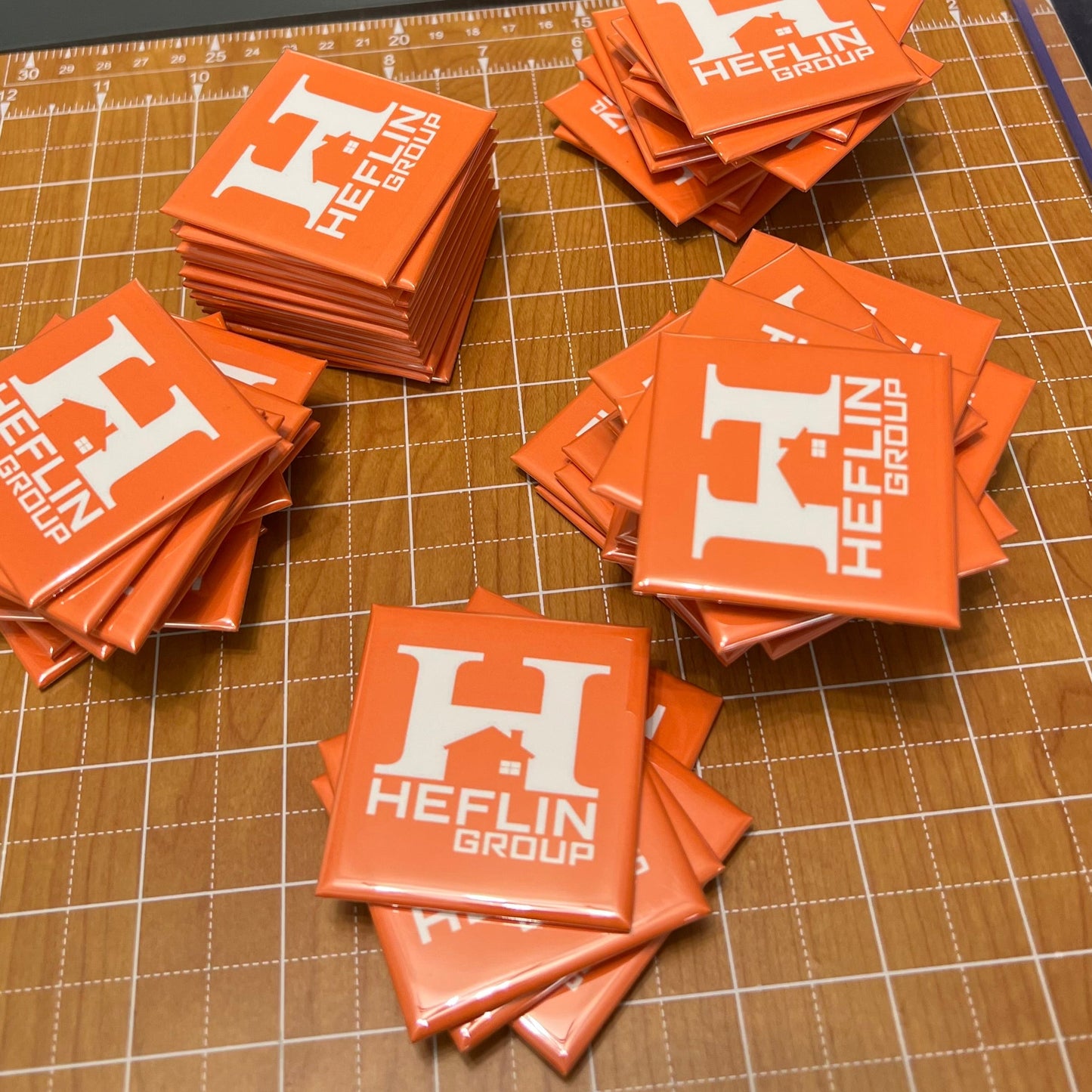 Stacks of orange stickers with 'Heflin Group' logo on a cutting mat with Trim Air logo.