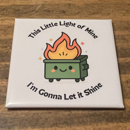 Square magnet with a cartoon fire and text on a wooden surface